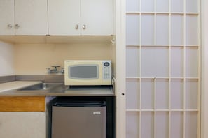 A kitchen with a microwave, a sink, and a small refrigerator. - Waikiki Heritage Hotel (Honolulu)