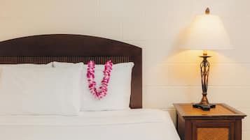A neatly made bed with white linens and a decorative lei.