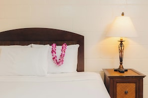 A neatly made bed with white linens and a decorative lei. - Waikiki Heritage Hotel (Honolulu)