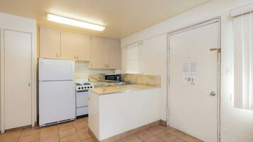A compact kitchen with a refrigerator, stove, microwave, and a small sink.
