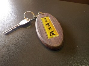 A wooden keychain with a metal key and a yellow label with black text. - Kosenkaku Yoshinoya (Totsukawa)