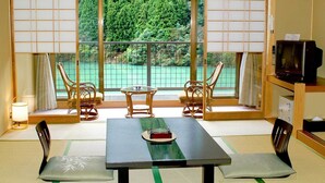 A traditional Japanese room with tatami flooring, a low table with cushions, and a television on a wooden stand. - Kosenkaku Yoshinoya (Totsukawa)
