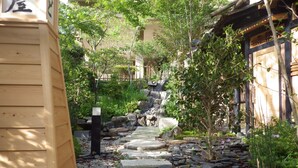 A traditional Japanese garden with a stone pathway leading to a wooden building. - Kosenkaku Yoshinoya (Totsukawa)