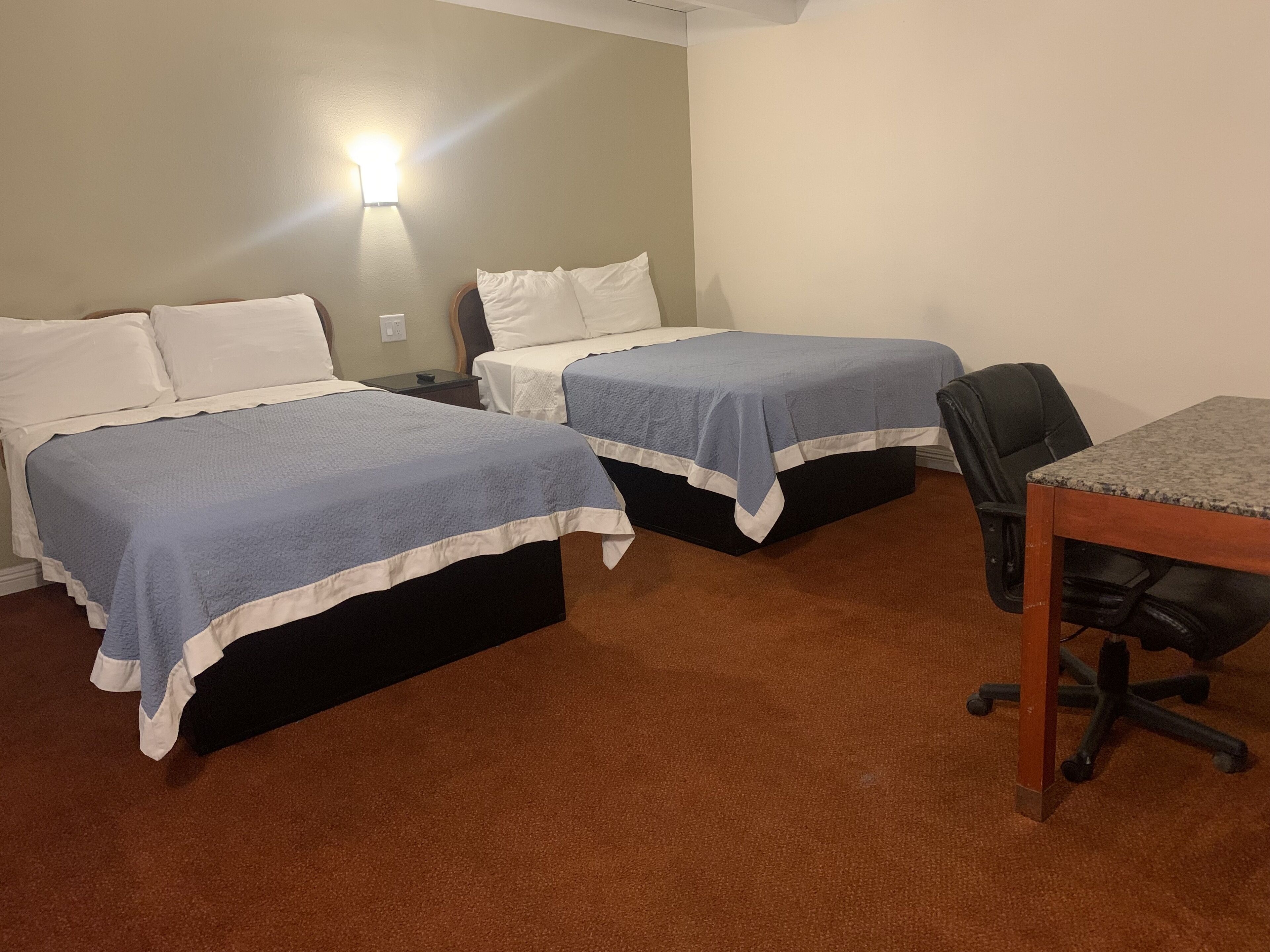 A room with two beds, a desk, and a chair.