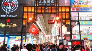 A busy street with various shops and signs, including a prominent 'WE GO' neon sign and a large illuminated sign with Japanese characters. - Hotel Trend NishiShinsaibashi (Osaka)
