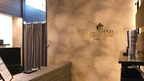 A hotel reception area with a textured wall, a reception desk, a glass display case, and a signboard. - Hotel Trend NishiShinsaibashi (Osaka)