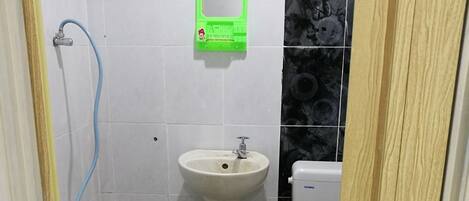 Ein kleines Badezimmer mit einem weißen Waschbecken, einer Toilette und einer Dusche.