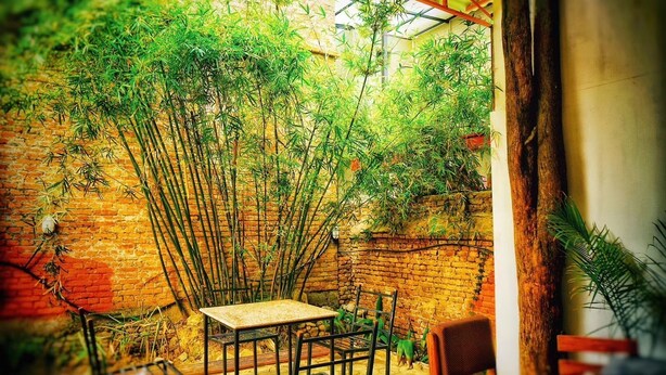 A rustic outdoor seating area with a brick wall and bamboo plants. - Himal Inn (Lalitpur)