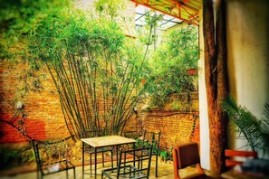 A rustic outdoor seating area with a brick wall and bamboo plants. - Himal Inn (Lalitpur)