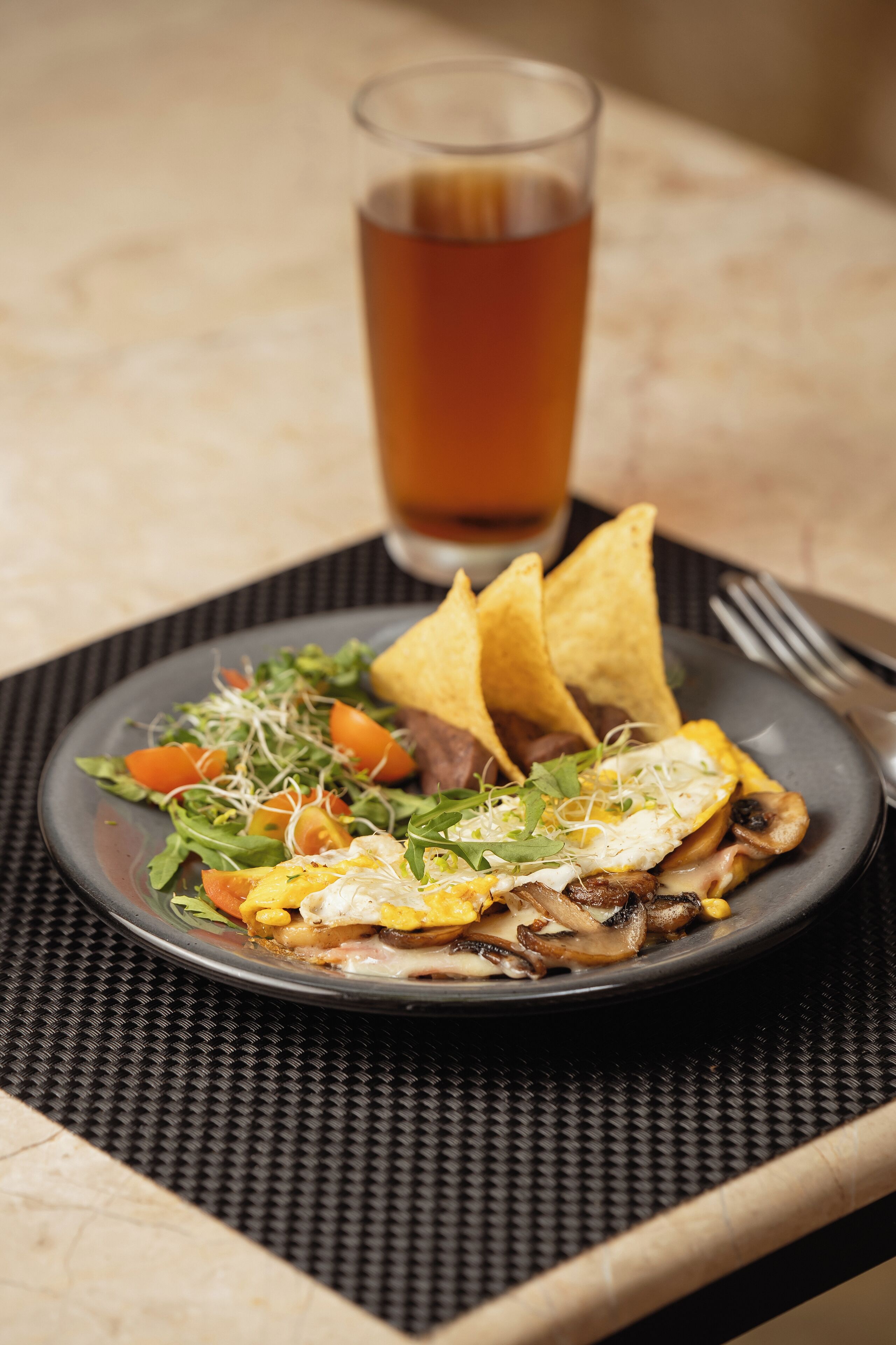 A plate of food with a glass of beverage on a table.