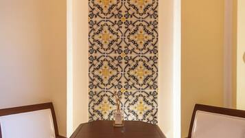 A dining area with two chairs, a table, and a decorative tile wall.