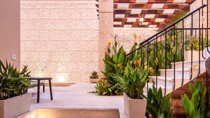 A staircase leading to a stone wall, surrounded by potted plants and a small table. - Casa Tavera (Mérida)