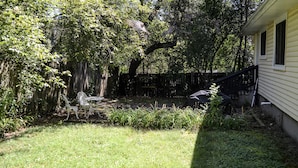 Ein Garten mit Holzzaun, einem weißen Stuhl und einem Tisch.