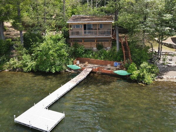 Une cabane avec un quai s’avançant dans une rivière, entourée d’une végétation luxuriante.