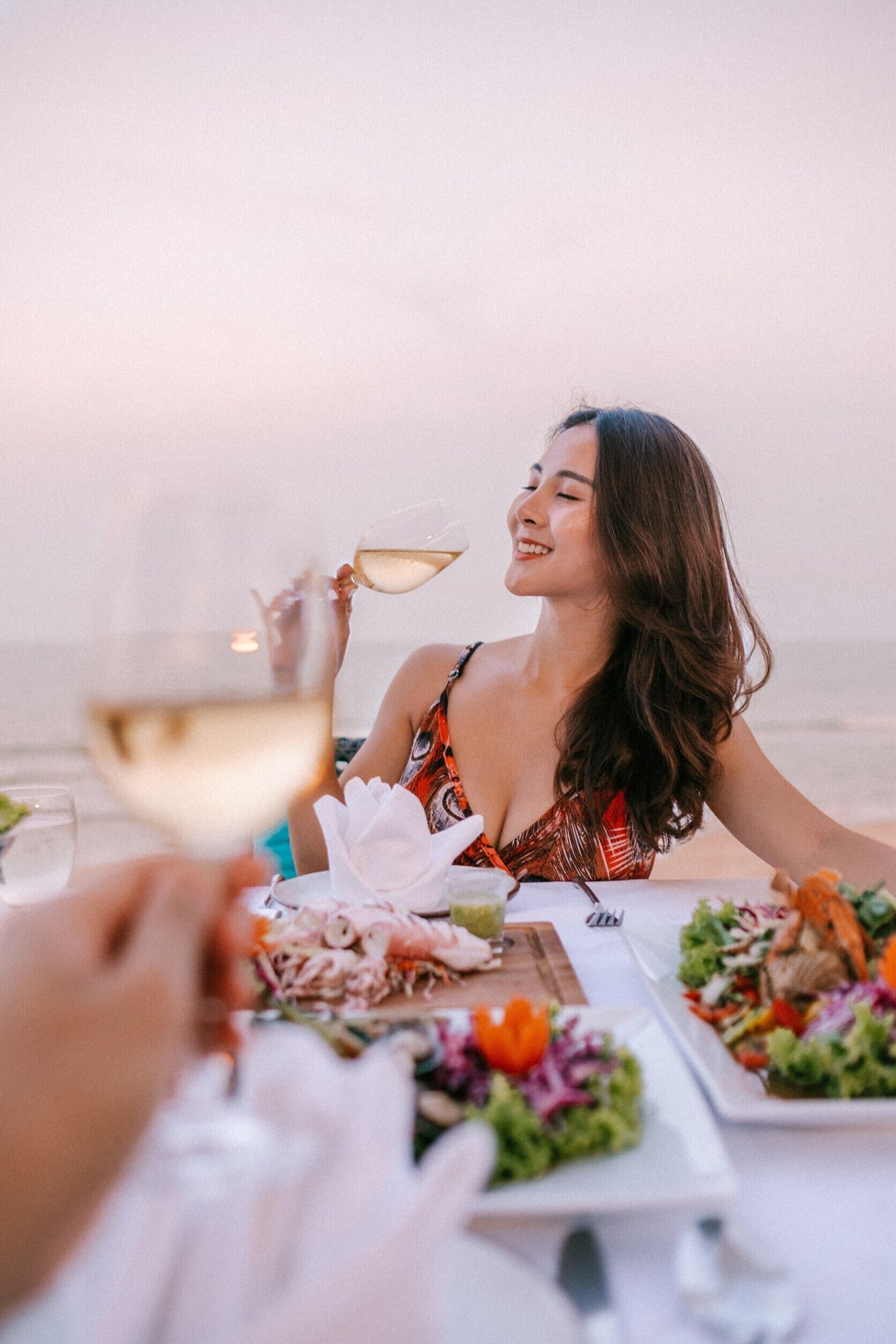 A dining table with plates of food and a glass of wine.