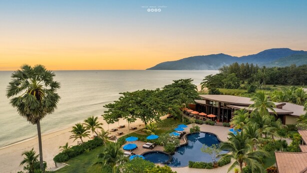 Un resort con piscina, playa y vistas a la montaña.