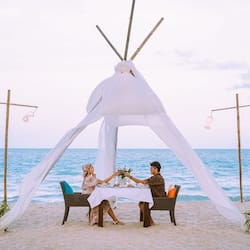 Romantic beachside dining under a charming teepee structure.
