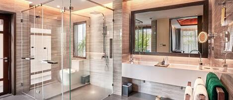 Un baño moderno con ducha de vidrio, un espejo grande y un tocador con lavamanos y toallero.