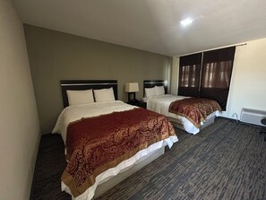 A hotel room with two beds, each with a headboard, a bedside table with a lamp, and a window with curtains. - Gateaway Motel Broken Bow NE (Broken Bow)
