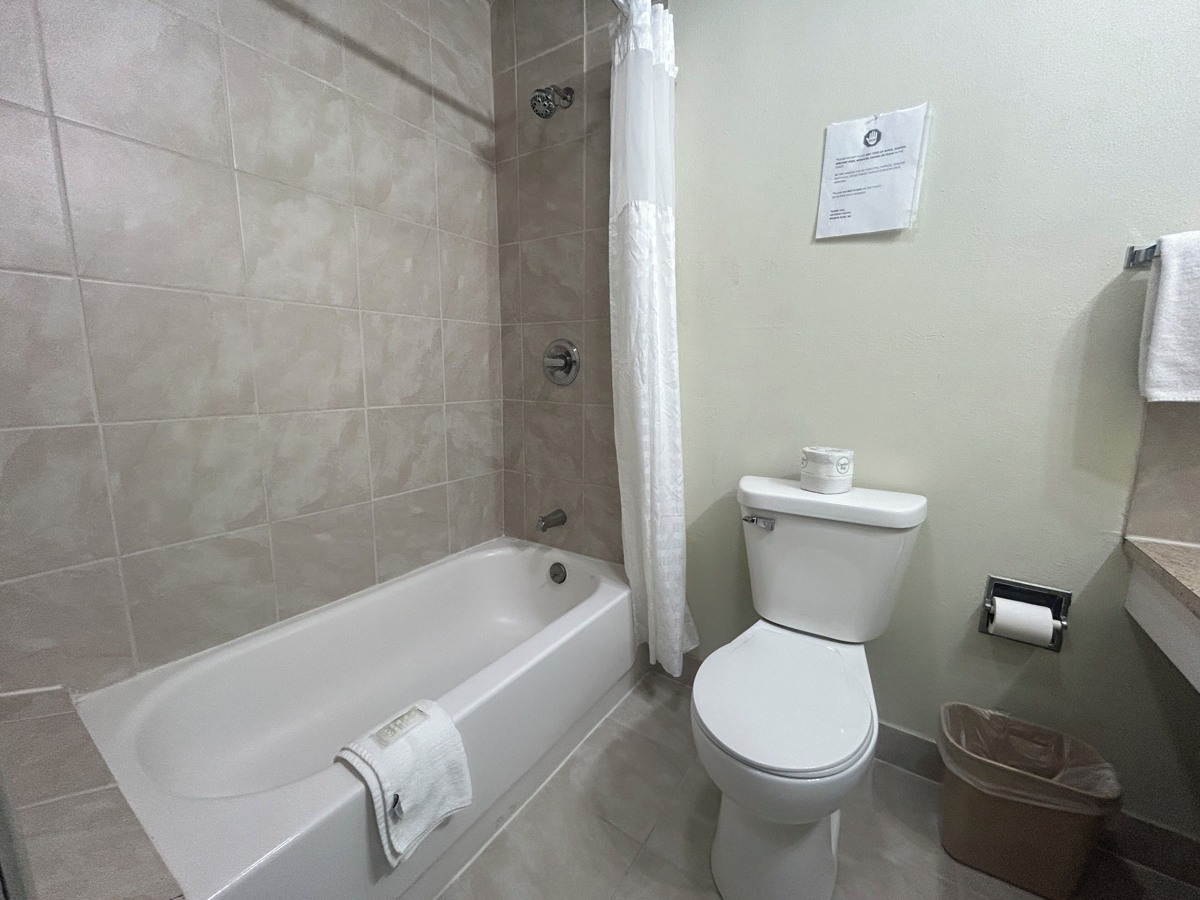 A bathroom with a bathtub, toilet, and shower curtain.