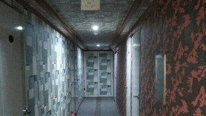 A hallway with patterned walls and doors, a tiled floor, and a ceiling with recessed lighting. - Gumi A Motel (Gumi)