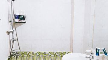 A bathroom with a shower, a sink, and a tiled floor.