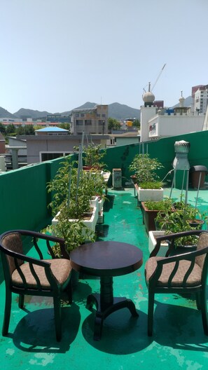 A rooftop terrace with green flooring, potted plants, and two wicker chairs around a small table. - Gumi A Motel (Gumi)