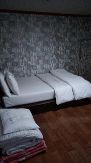 A room with a bed, a small table, and a wall with a repeating pattern. - Gumi A Motel (Gumi)