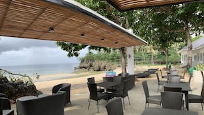 An outdoor seating area with wicker furniture overlooking a beach.