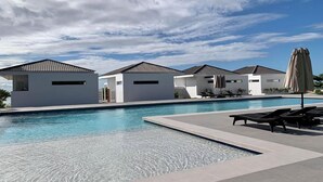 A modern pool area with clear blue water, white buildings, and lounge chairs.