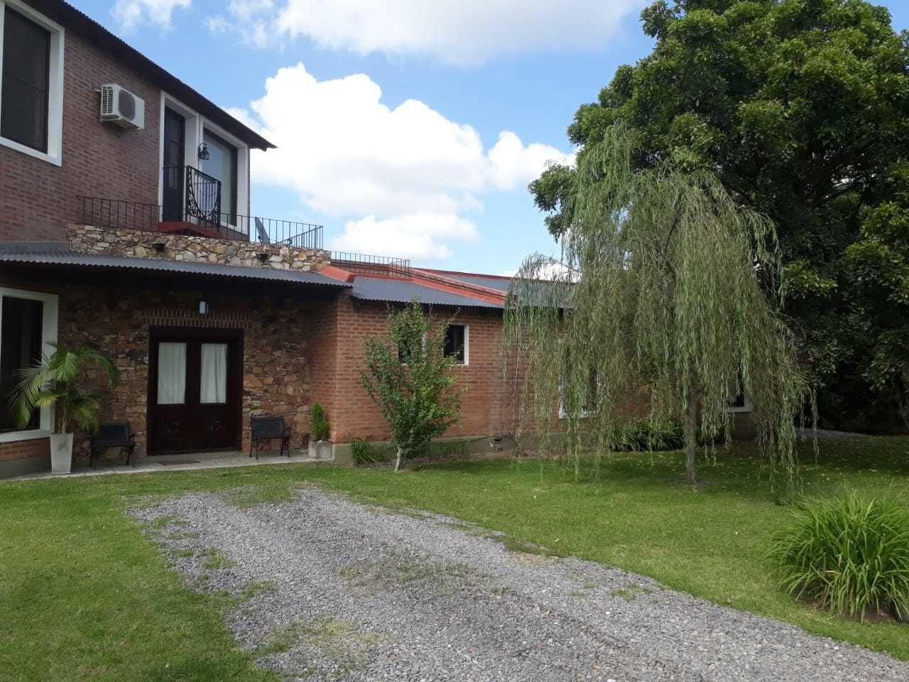 A two-story house with a stone facade, a balcony, and a well-maintained lawn.