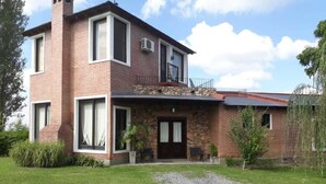 Une maison à deux étages avec une façade en pierre, un balcon et une allée gravillonnée.