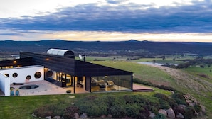 A modern house with a glass facade, a flat roof, and a view of the countryside. - Sky High: stunning, iconic, dramatic (Mount Franklin)