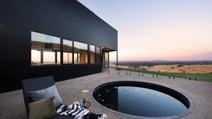 A modern building with large windows, a circular hot tub, and a view of a landscape. - Sky High: stunning, iconic, dramatic (Mount Franklin)