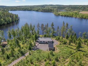 Un chalet au bord du lac, avec une allée pavée et un petit espace de stationnement.