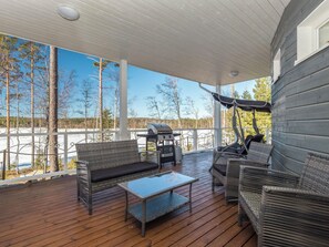 Un espace extérieur aménagé avec des meubles en osier, une table basse en verre et un barbecue, le tout abrité.