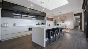 Une cuisine moderne dotée d’un îlot central, de tabourets de bar et d’un coin repas avec une table et des chaises.