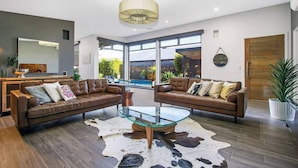 Un salon moderne avec des canapés en cuir, une table basse en verre et un tapis en peau de vache.
