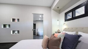 Une chambre à coucher moderne avec un grand lit, une tête de lit et une vue sur la salle de bain.