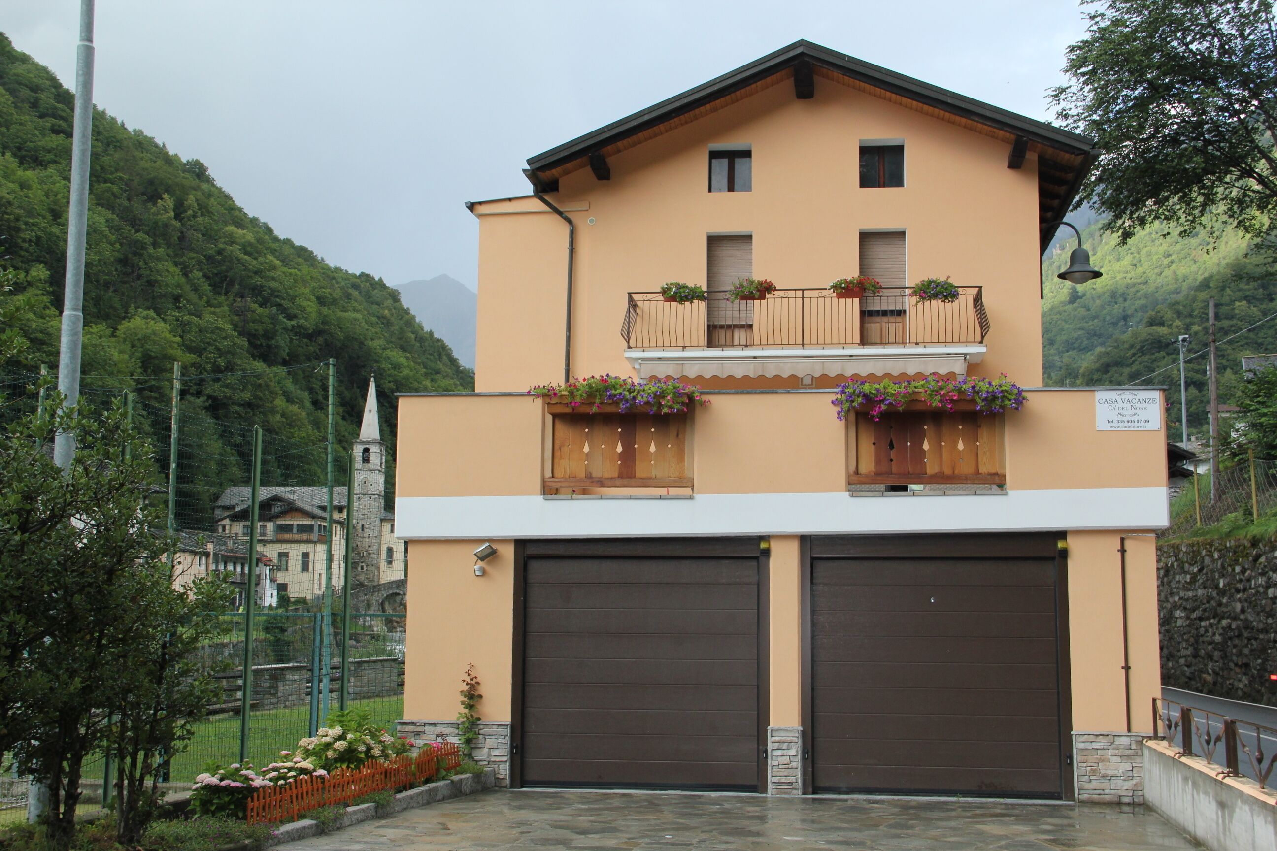 A two-story building with a balcony, a garage, and a sign indicating it's a vacation rental.