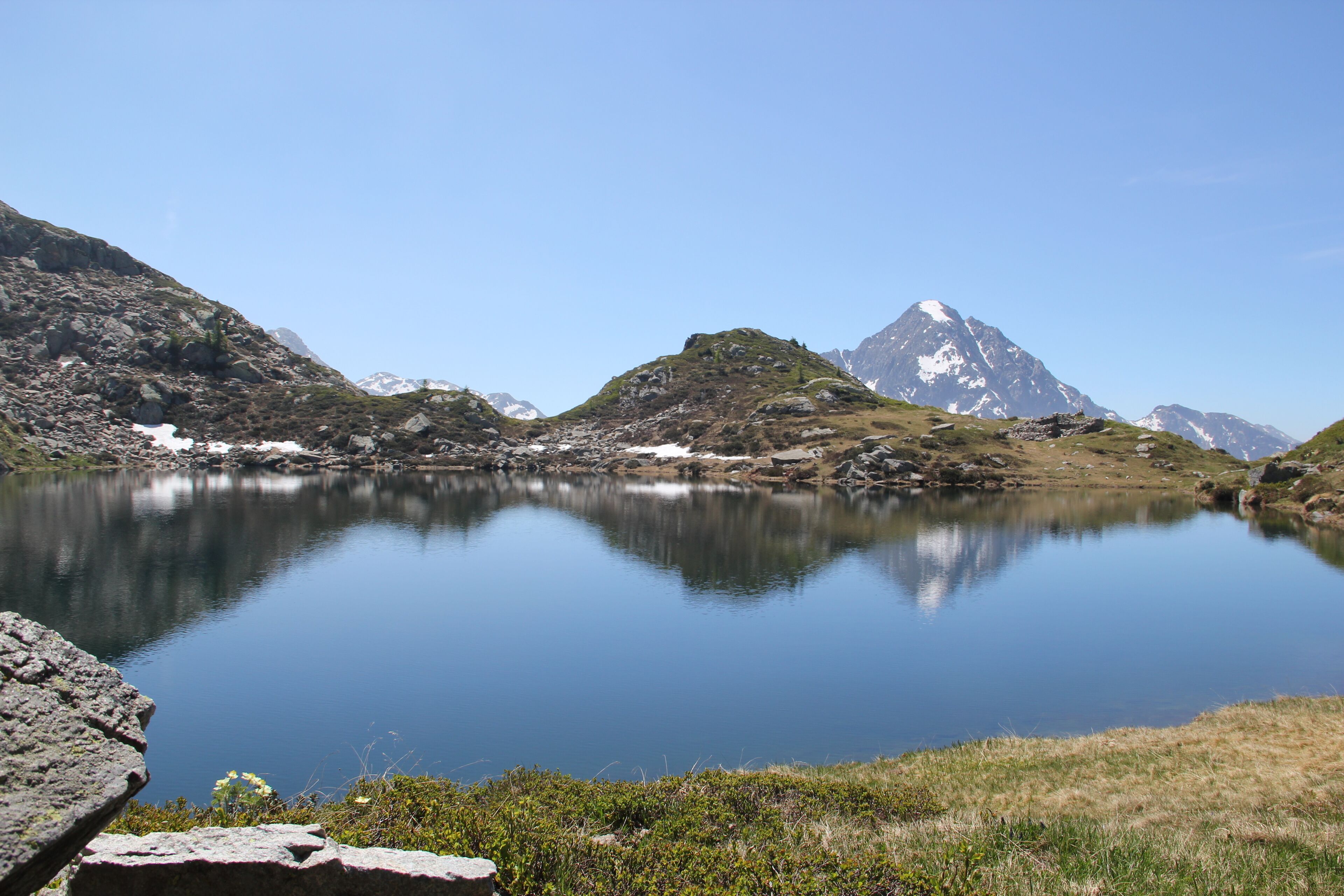A tranquil lake surrounded by mountains with clear skies.