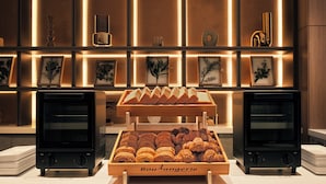 A bakery display with pastries and bread, two ovens, and a wall with framed pictures. - SONO Moon Nagoya  (Nagoya)
