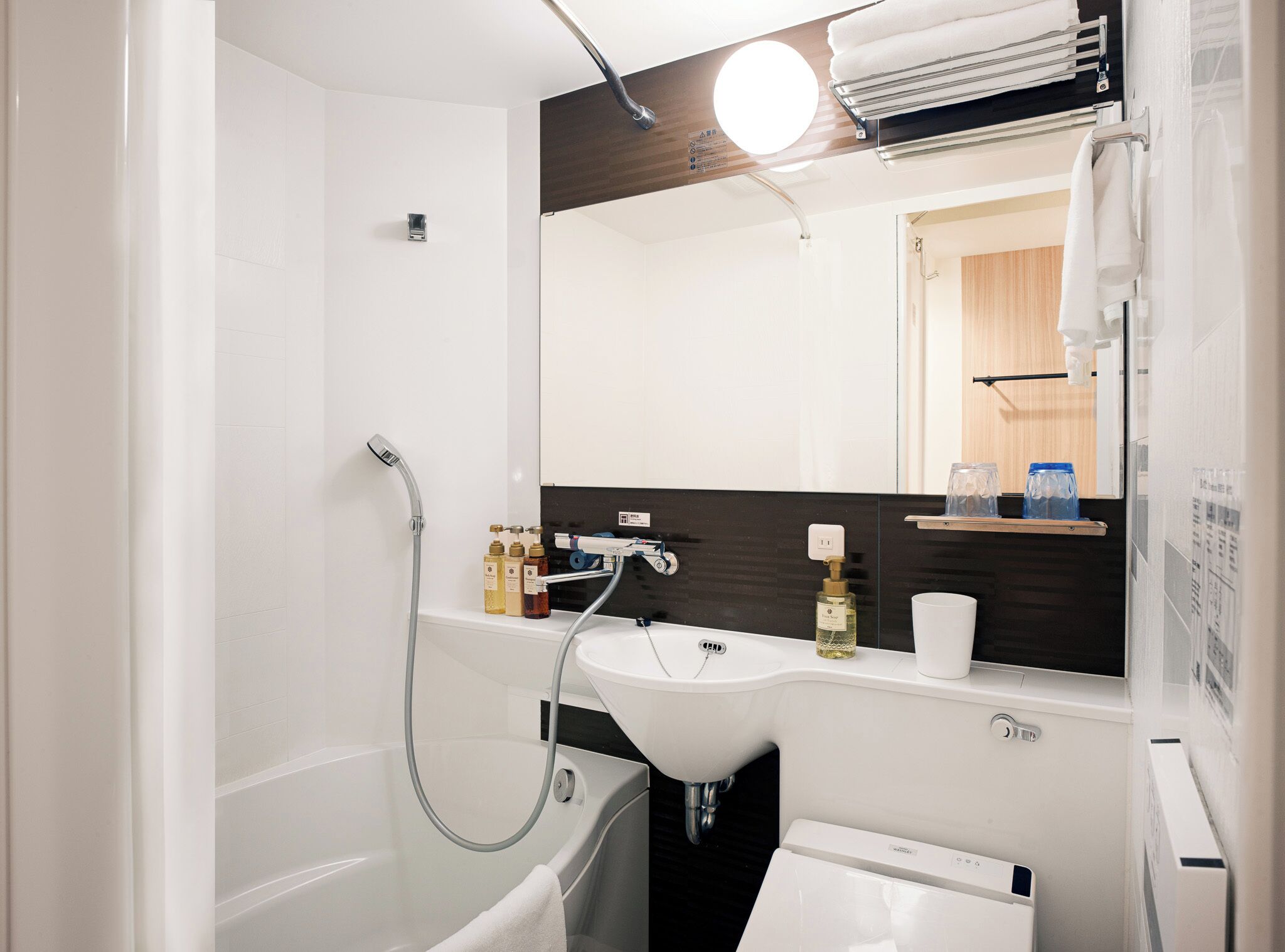 A modern bathroom with a bathtub, a sink, a mirror, and a towel rack.
