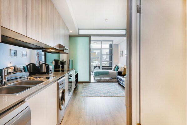 A modern kitchen with stainless steel appliances, a built-in oven, and a large window offering a city view.