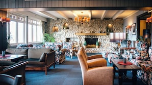 Una sala de estar acogedora con una pared de piedra, chimenea y muebles con estampado floral.