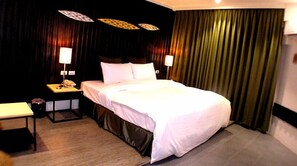 Una habitación de hotel con una cama grande, dos mesitas de noche y un escritorio.