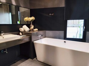 Un baño moderno con una bañera grande, dos lavamanos y un espejo.