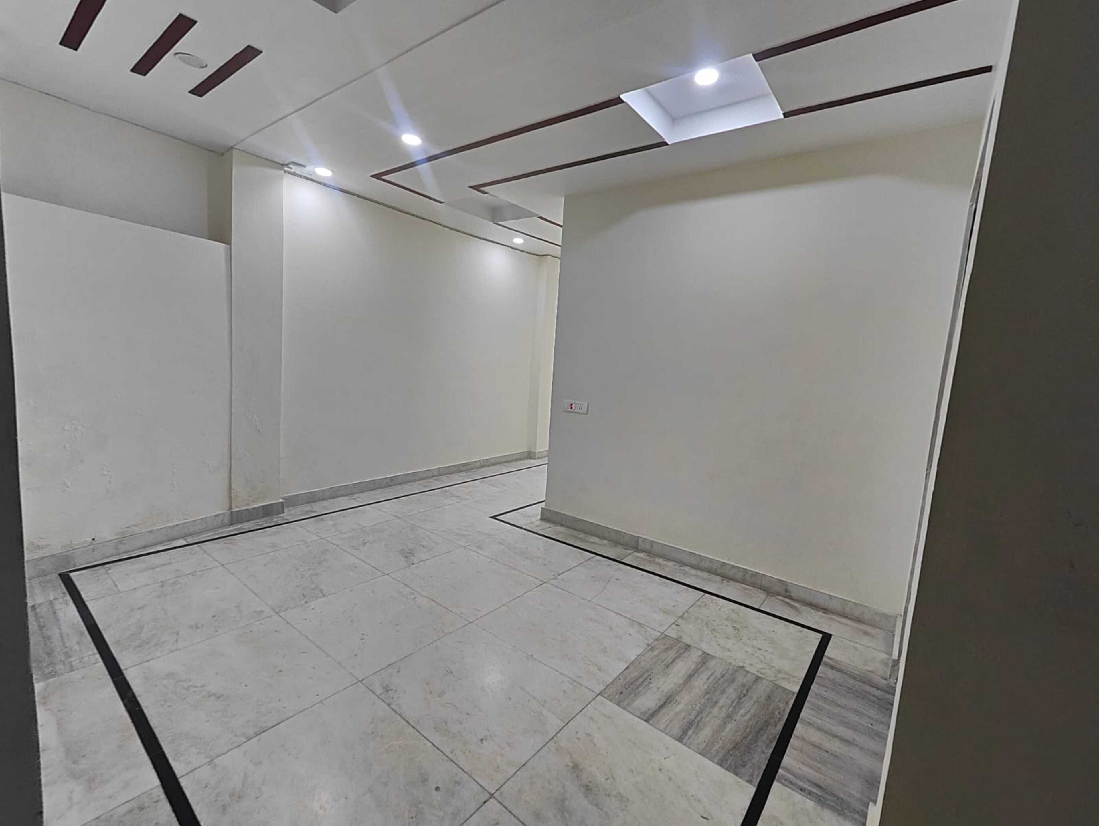 Una habitación amplia y vacía con piso de baldosas y un diseño de techo moderno y sencillo.