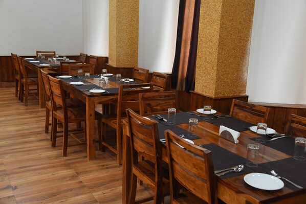 A long wooden dining table with chairs, set for a meal.