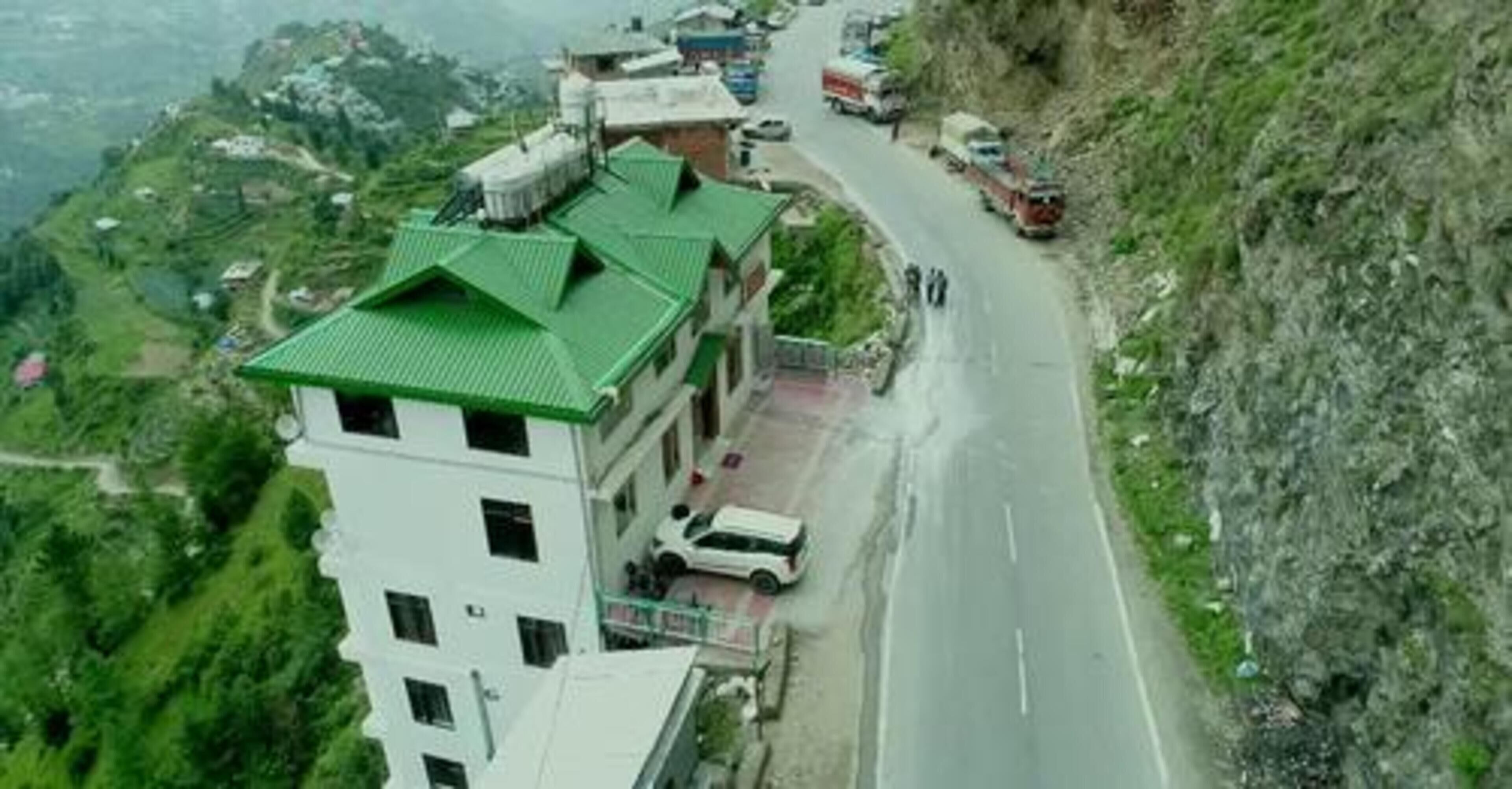 A building with a green roof, adjacent to a road with vehicles.